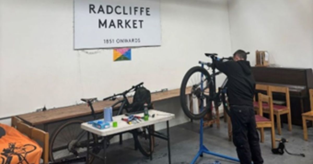 a man undertaking bike maintenance inside Radcliffe Market Hall