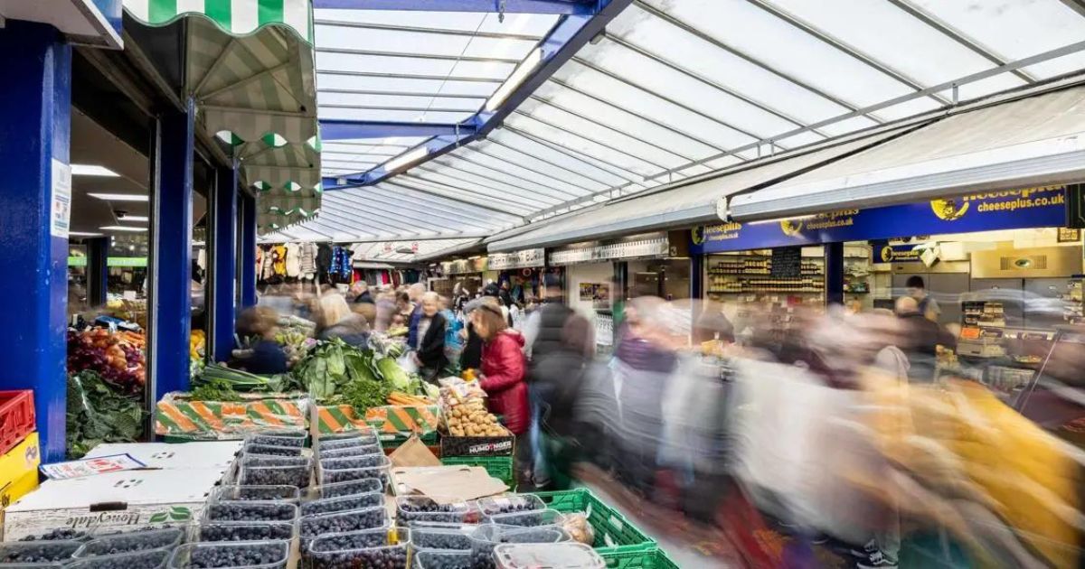 A bustling Bury Market with tubs of berries and vegetables on show.