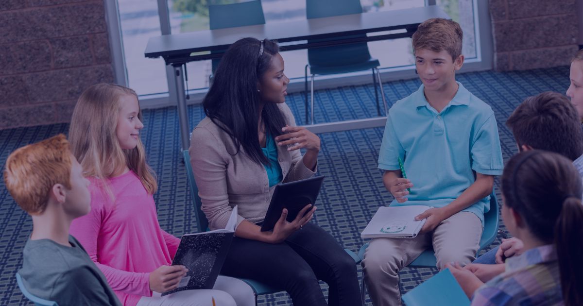 A group of children sitting in a circle with an adult facilitator, participating in a group activity