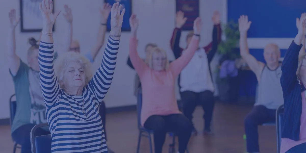 a group of males and females undertaking gentle chair based exercises