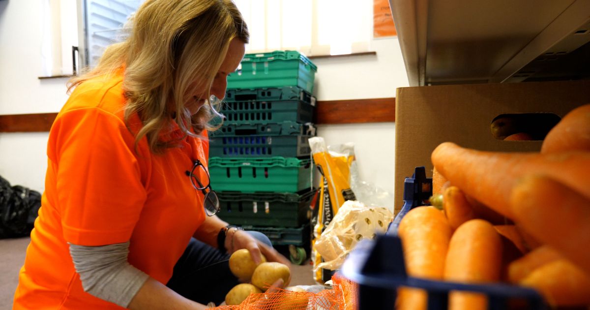 a lady preparing and sorting food items such as potatoes and carrots ready for distributing at the food bank.