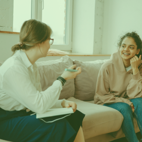 A woman sat on a sofa talking to another woman