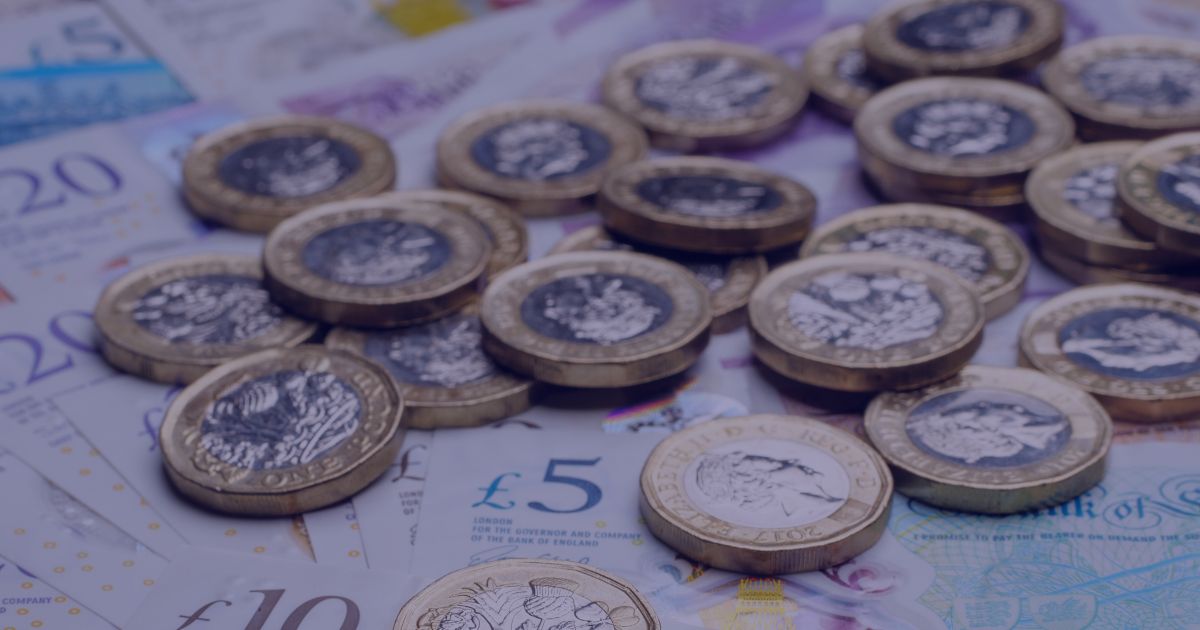 a pile of pound coins on top of some £5, £10, and £20 notes.