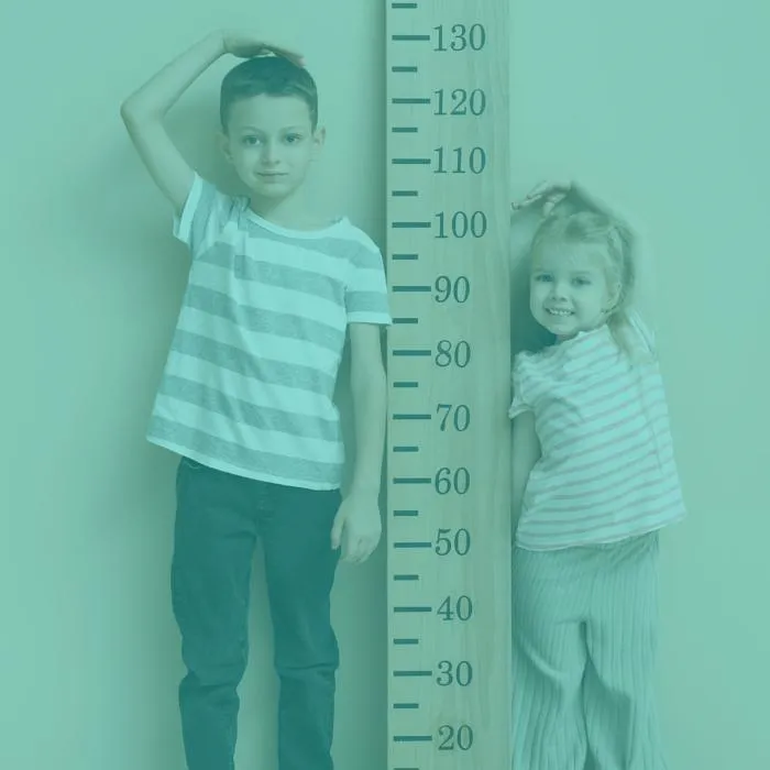 a boy and a girl stand either side of a measuring stick