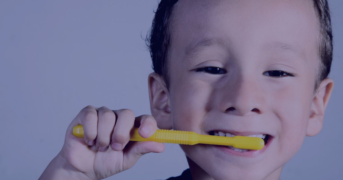 a boy smiling toothily while holding a bright yellow toothbrush. The calming light blue background adds a soothing touch, making this visually engaging and appealing scene.
