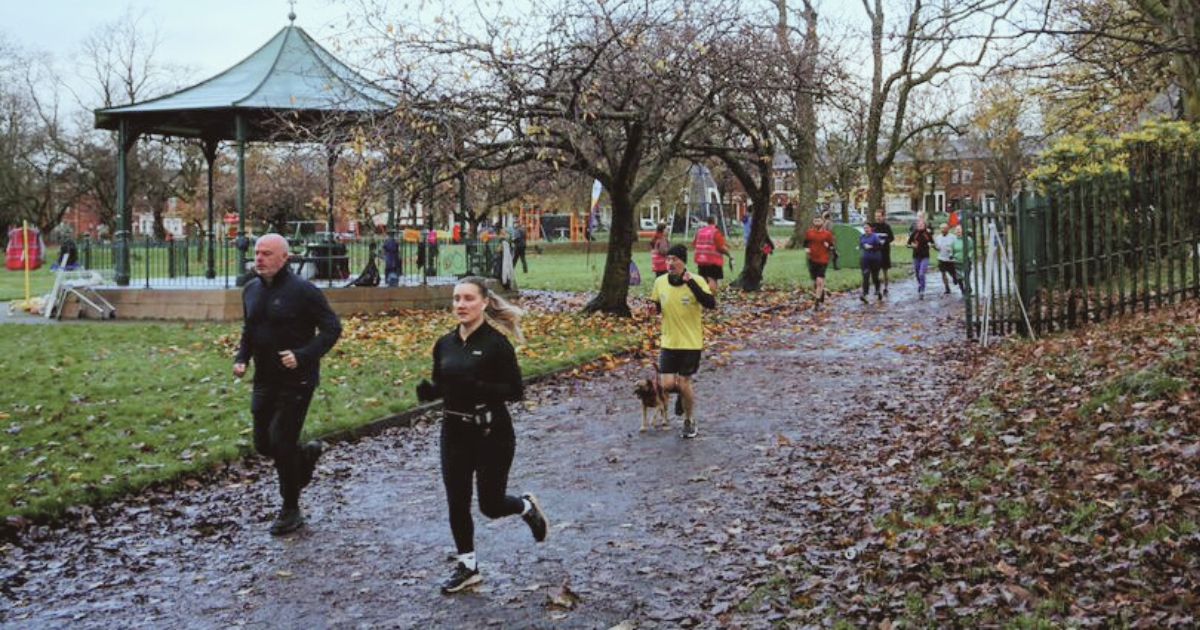 A group of people running through Clarence Park, Bury