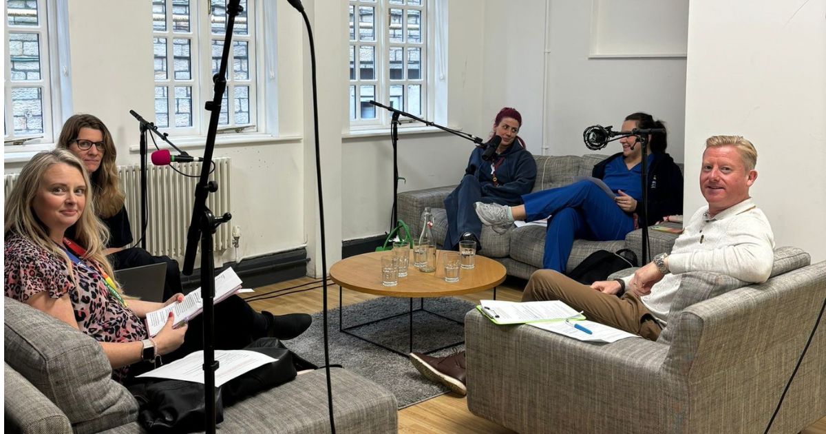 a group of people sat on sofas in a recording studio with microphones positioned accordingly