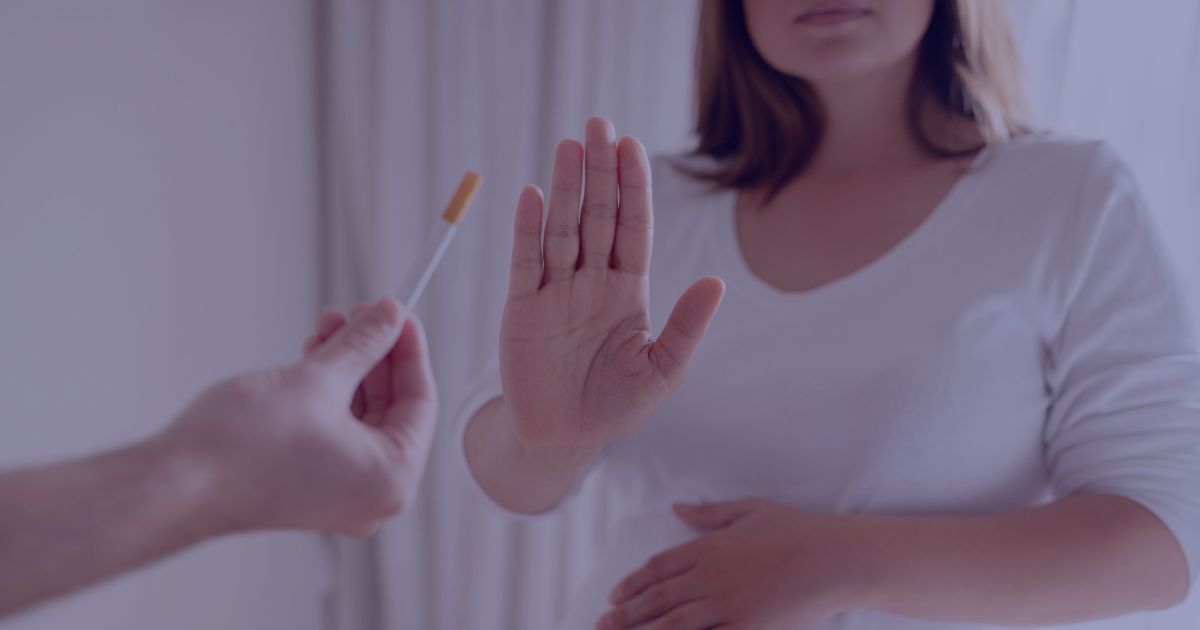 A hand reaches out to offer a pregnant lady a cigarette, who holds her hand out declining the offer.