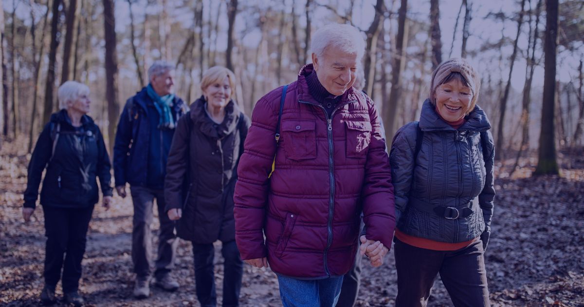 a group of 5 men and women walking together and smiling and laughing