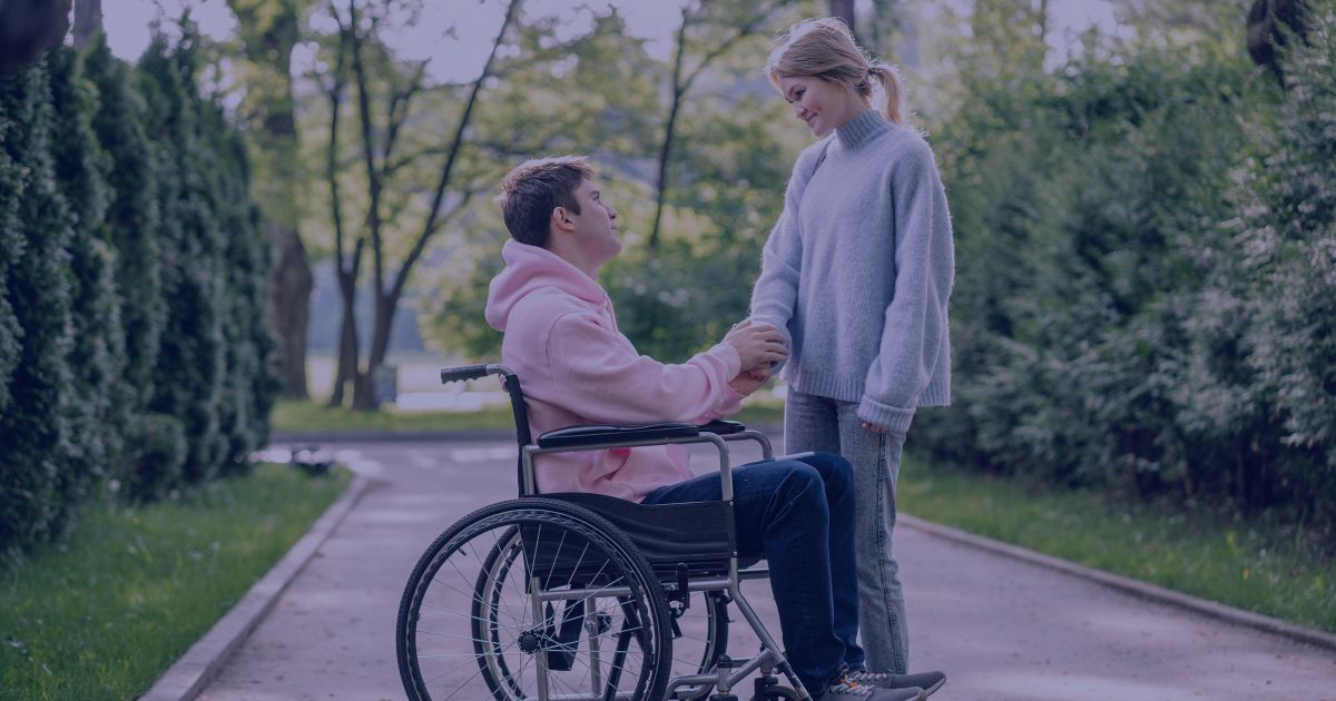 a young man in a wheelchair holding hands with a female friend