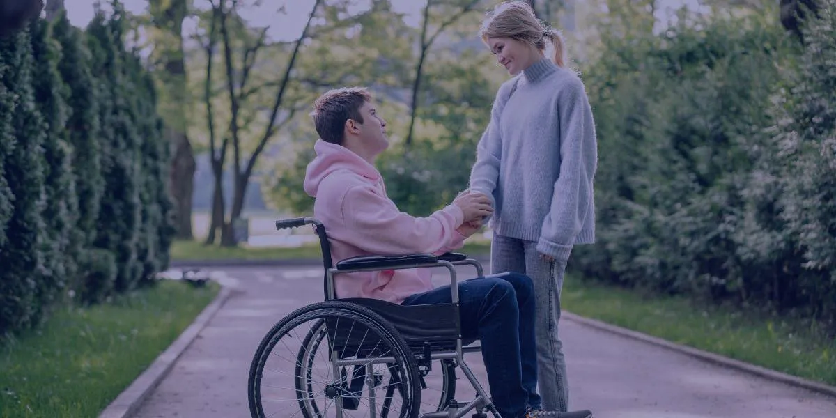 a young man in a wheelchair holding hands with a female friend