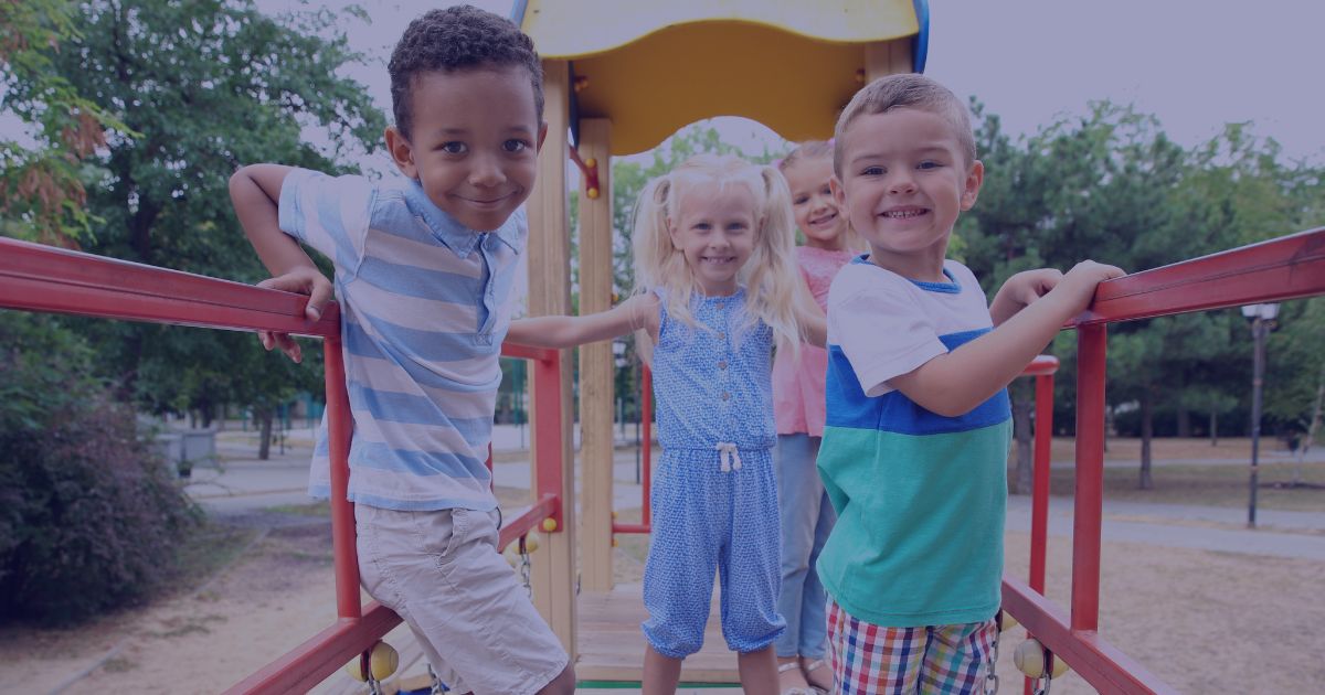 A group of children engaging with various playground structures, including slides and climbing frames, in a vibrant park.