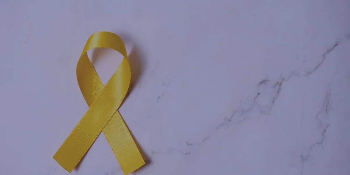 Yellow awareness ribbon on a marble background symbolizing suicide prevention and mental health awareness.