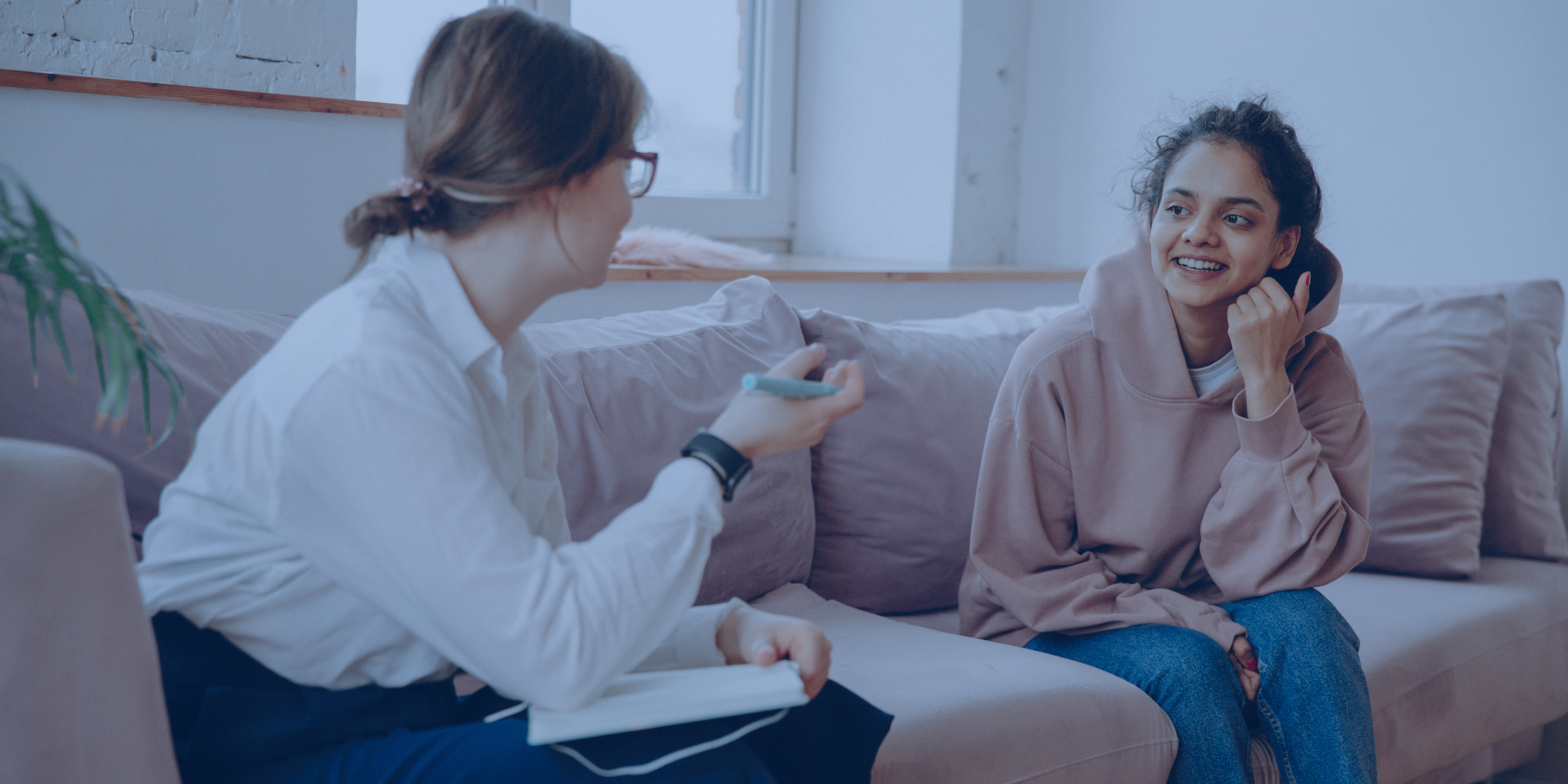 Two women sat on a sofa chatting