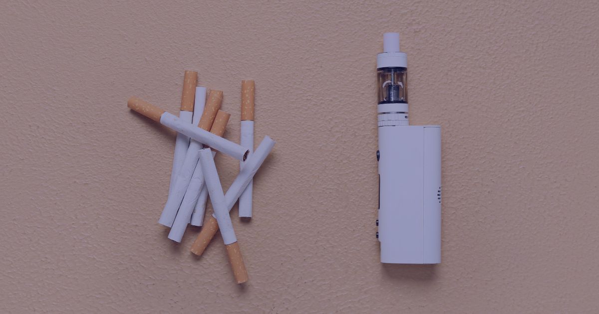 a handful of unlit cigarettes piled up on a table, alongside an electronic cigarette