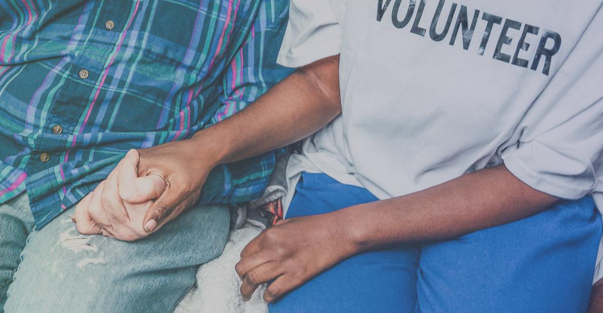 Two people holding hands while seated side by side.