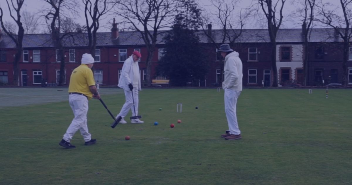 a group of men play croquet in a Bury park