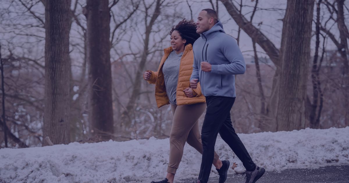 a man and a women jogging down a snowy path