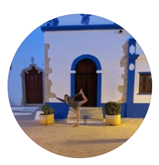 image of woman in yoga pose outside a white & blue buidling